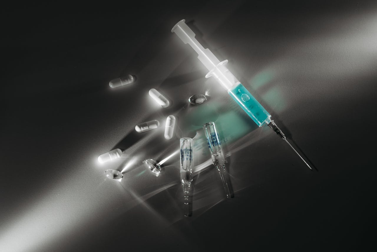 about-02 Syringe and medicine capsules illuminated in a dark, dramatic setting, emphasizing medical themes.