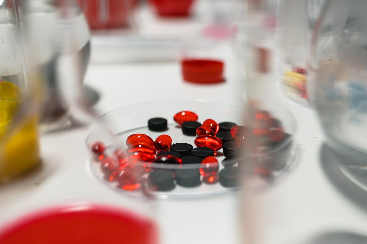 about-03 Close-up view of red and black pills on a lab table with blurred background.